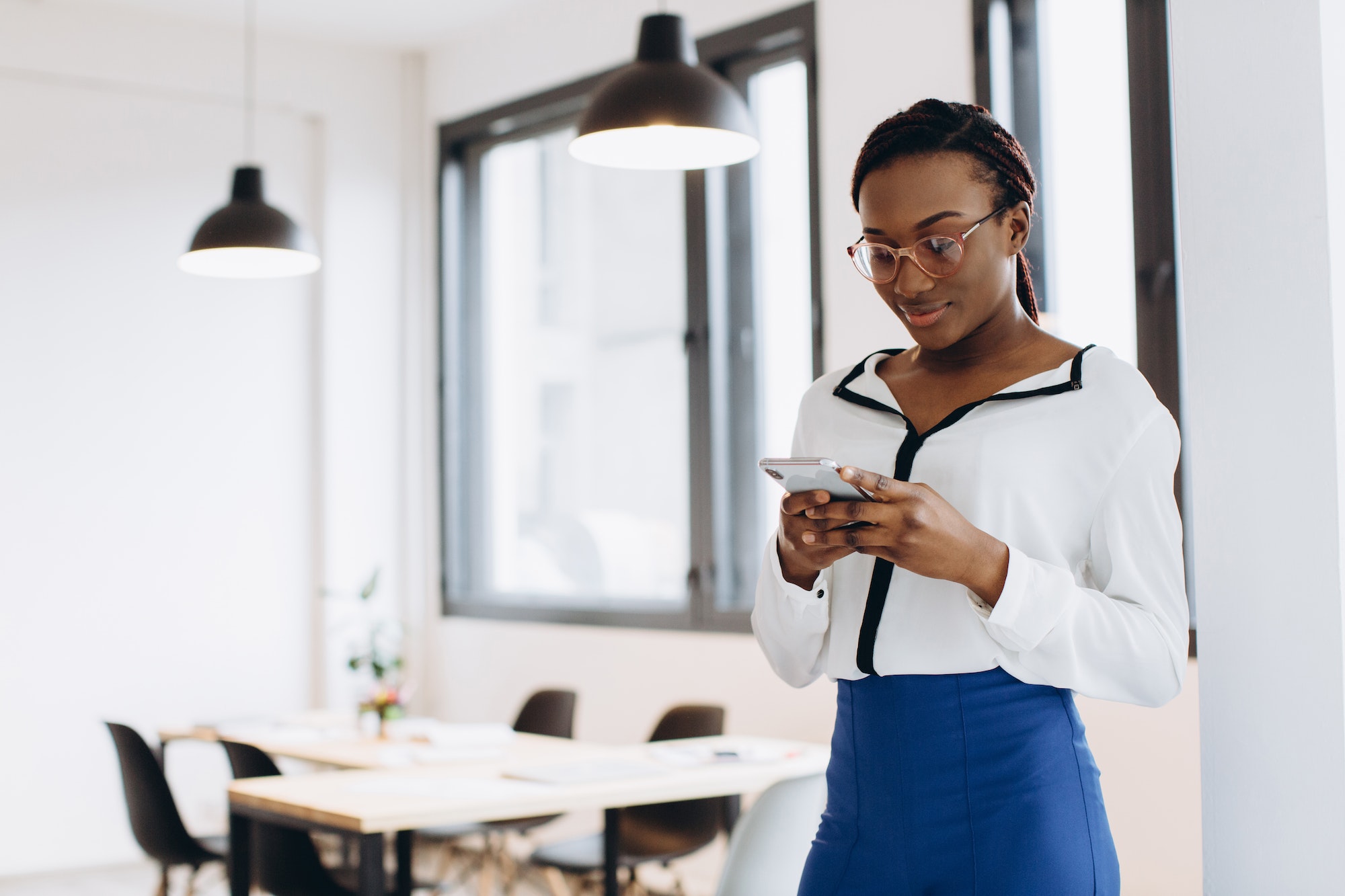 Beautiful african corporate worker talking on mobile phone in modern office